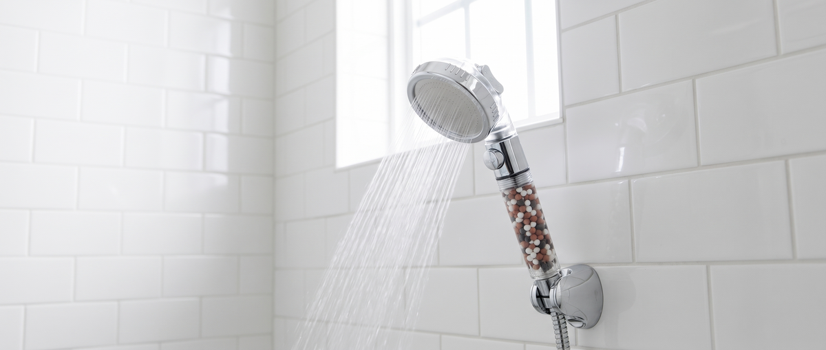 The Sorelle Three-Mode Shower Head in a wall bracket with water running